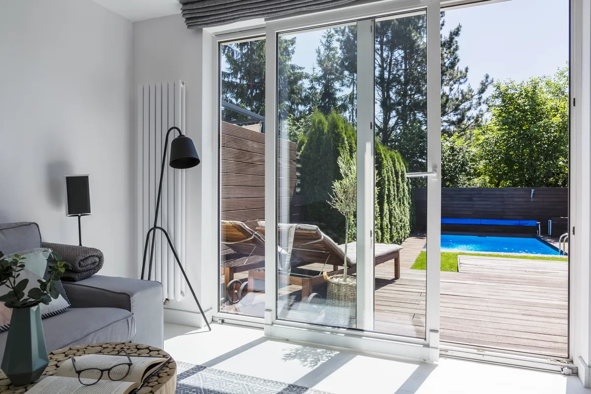 Grey aluminium bi-fold doors opening from a living room onto a garden and pool