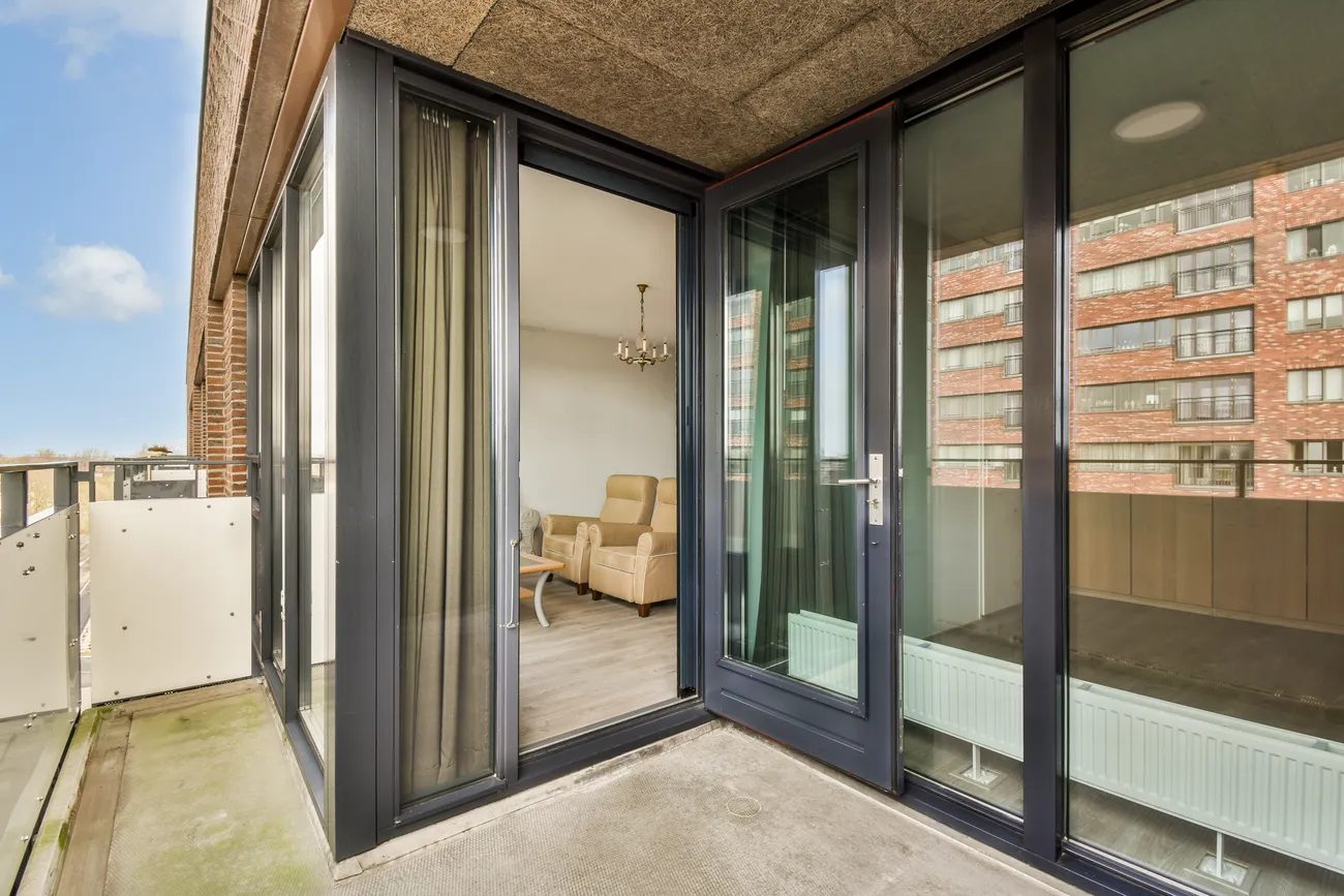 Black aluminium bi-fold doors wrapping a building corner onto a balcony