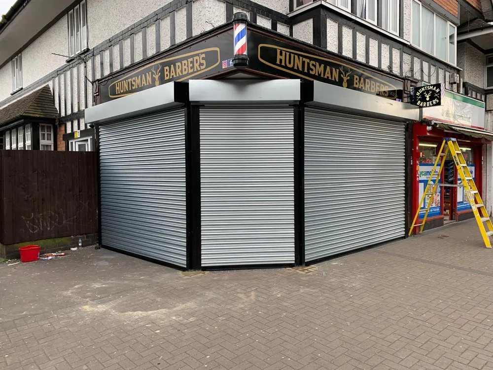 Silver roller shutters fitted to a corner barbershop in London by Range Shop Fronts