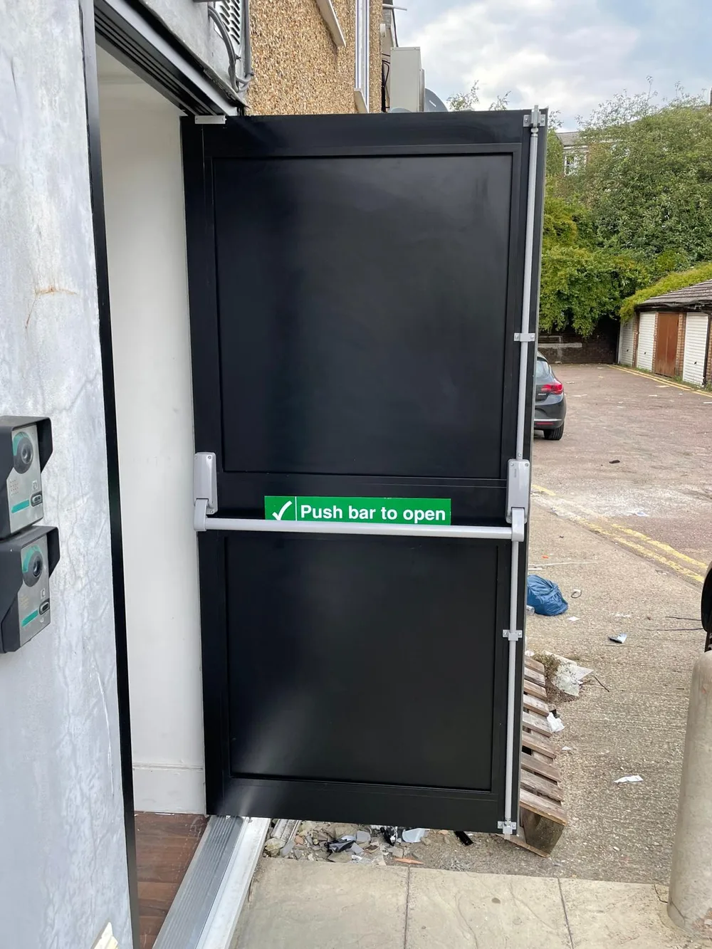 Steel security door fitted with panic-bar exit hardware